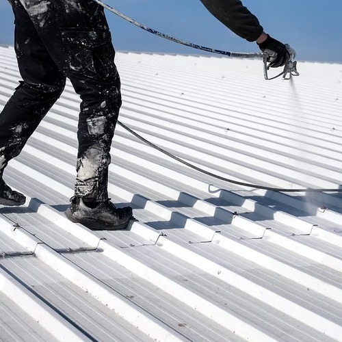 worker applying a metal roof coating