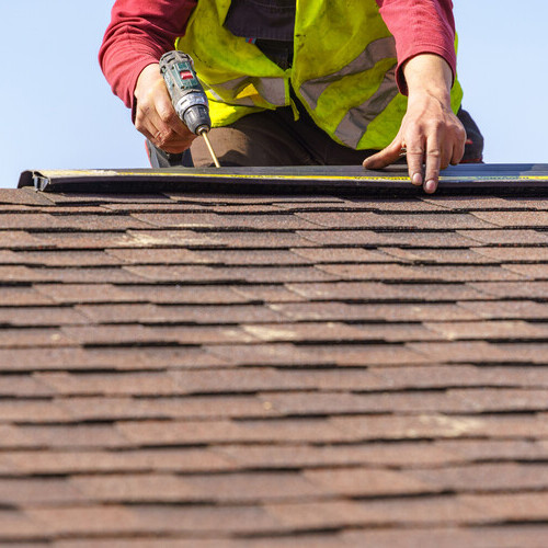worker repairing a shingle roof